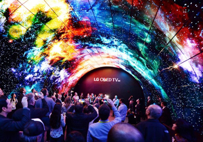 A crowd of people from CES standing underneath the LG ceiling displays showing a beautiful and colorful pattern